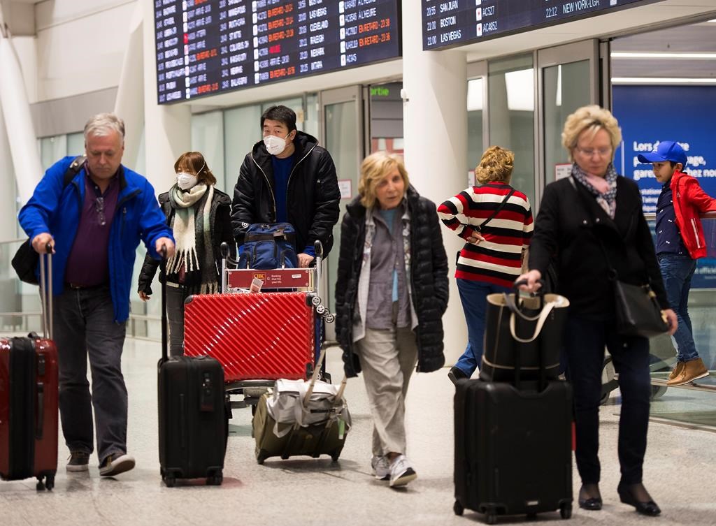 People wear masks as a precaution due to the coronavirus outbreak as they arrive at the International terminal at Toronto Pearson International Airport in Toronto on Saturday, January 25, 2020. As of tomorrow, vaccinated travellers will no longer need a COVID-19 test to enter Canada.