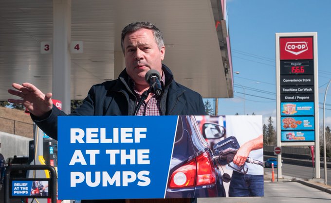 Premier Jason Kenney at a gas station standing at a podium that reads "relief at the pumps"