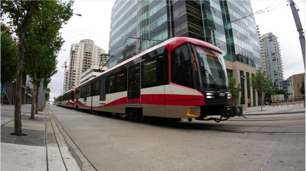 A red and white Ctrain makes it way along 7 Ave SW in downtown Calgary