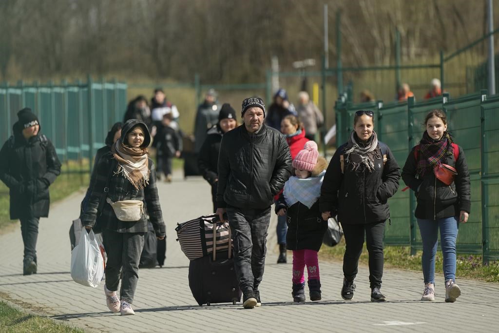 Refugees walk after fleeing the war from neighbouring Ukraine at the border crossing in Medyka