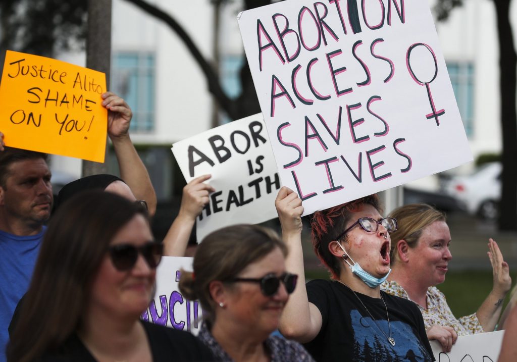 A woman holds a sign that says "Abortion Access Saves Lives"