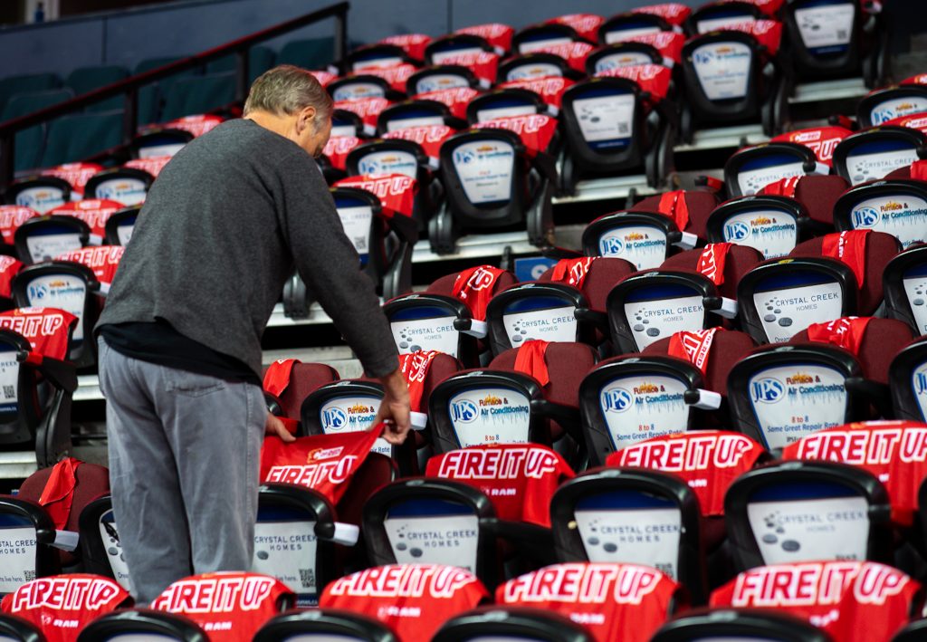 A Saddledome worker placing Flames towels on the seats.