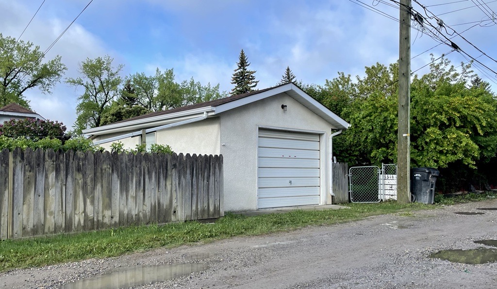 A garage in an alleyway is seen with a fence next to it