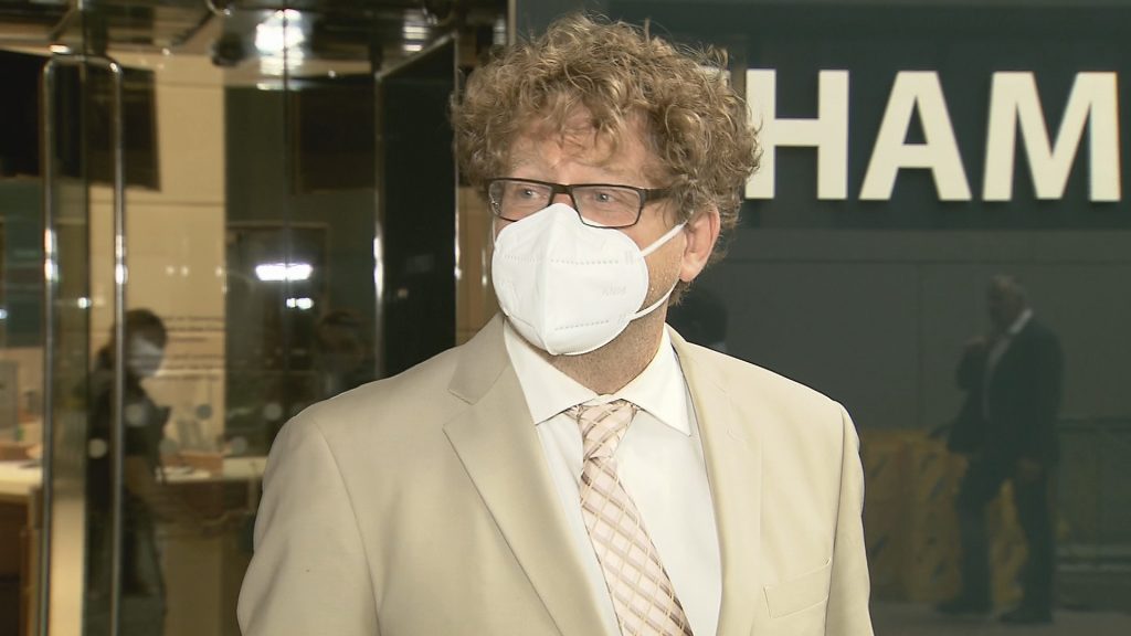 Calgary Ward 9 councillor Gian-Carlo Carra speaks to reporters wearing a face mask and a light coloured suit and tie