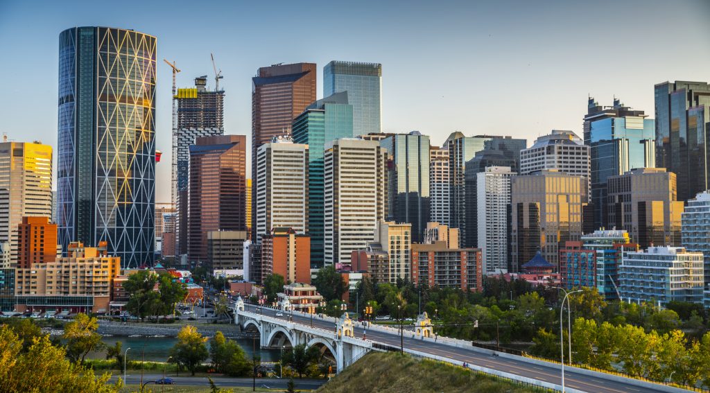 Calgary's skyline with its skyscrapers and office buildings. Bow river and Centre Street Bridge in the foreground.