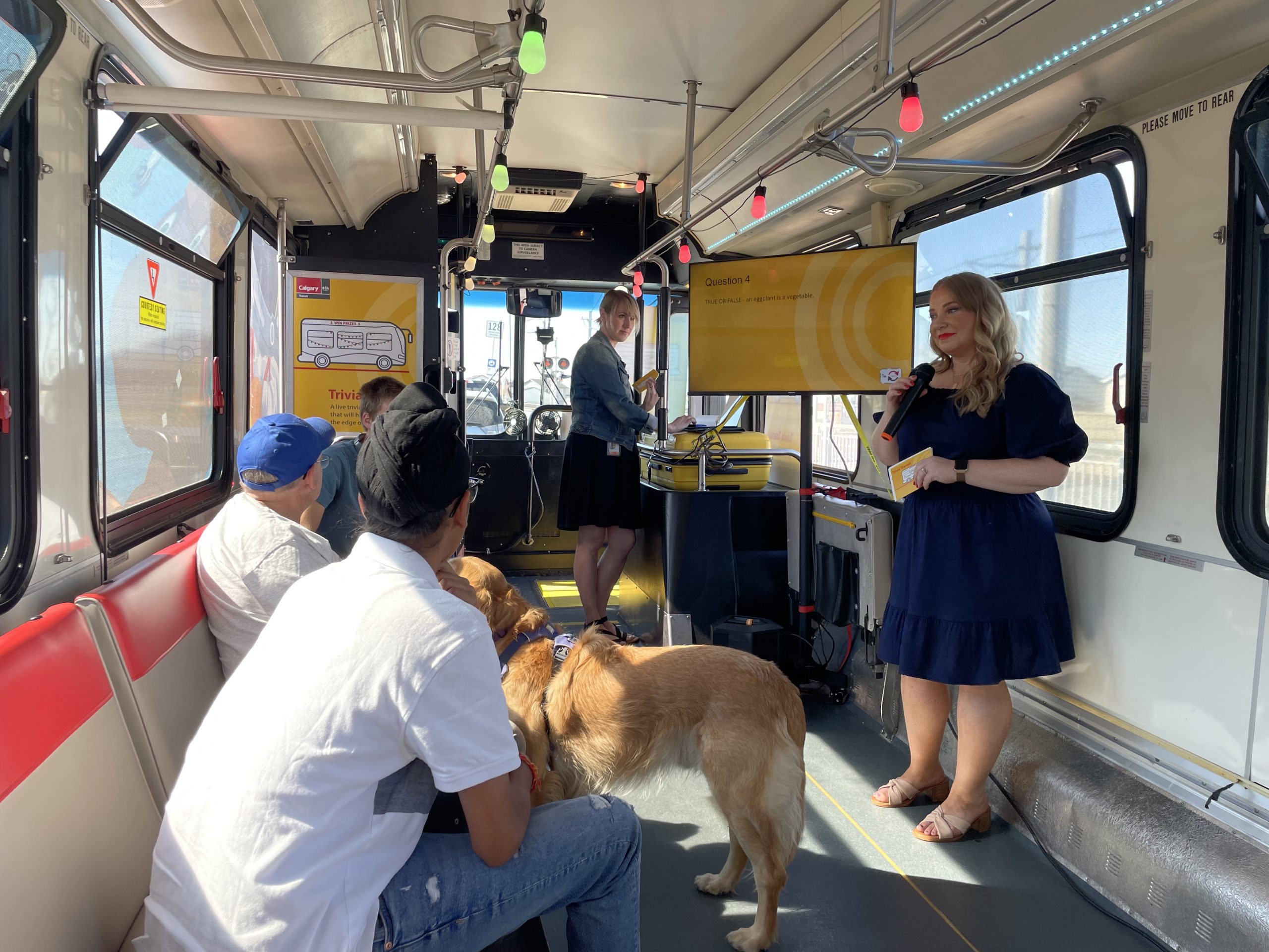 A woman asks Calgary Transit riders questions inside the Calgary Transit Trivia bus