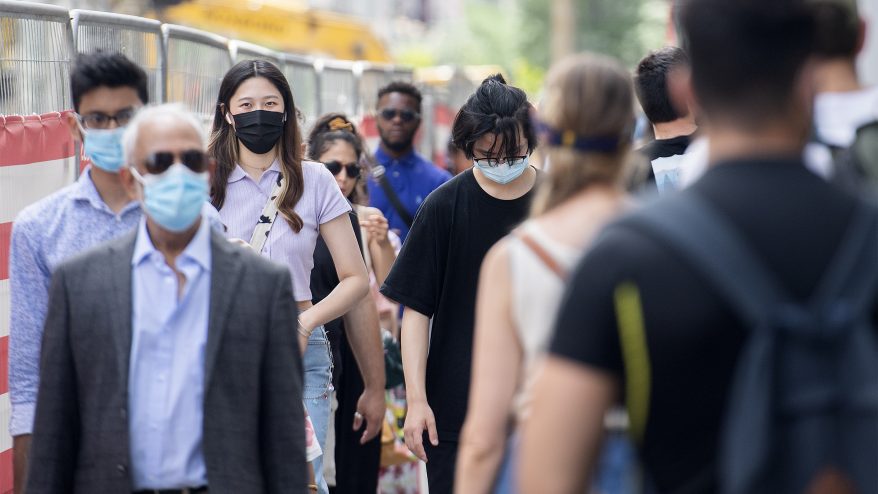 People wear face masks as they walk along a street in Montreal