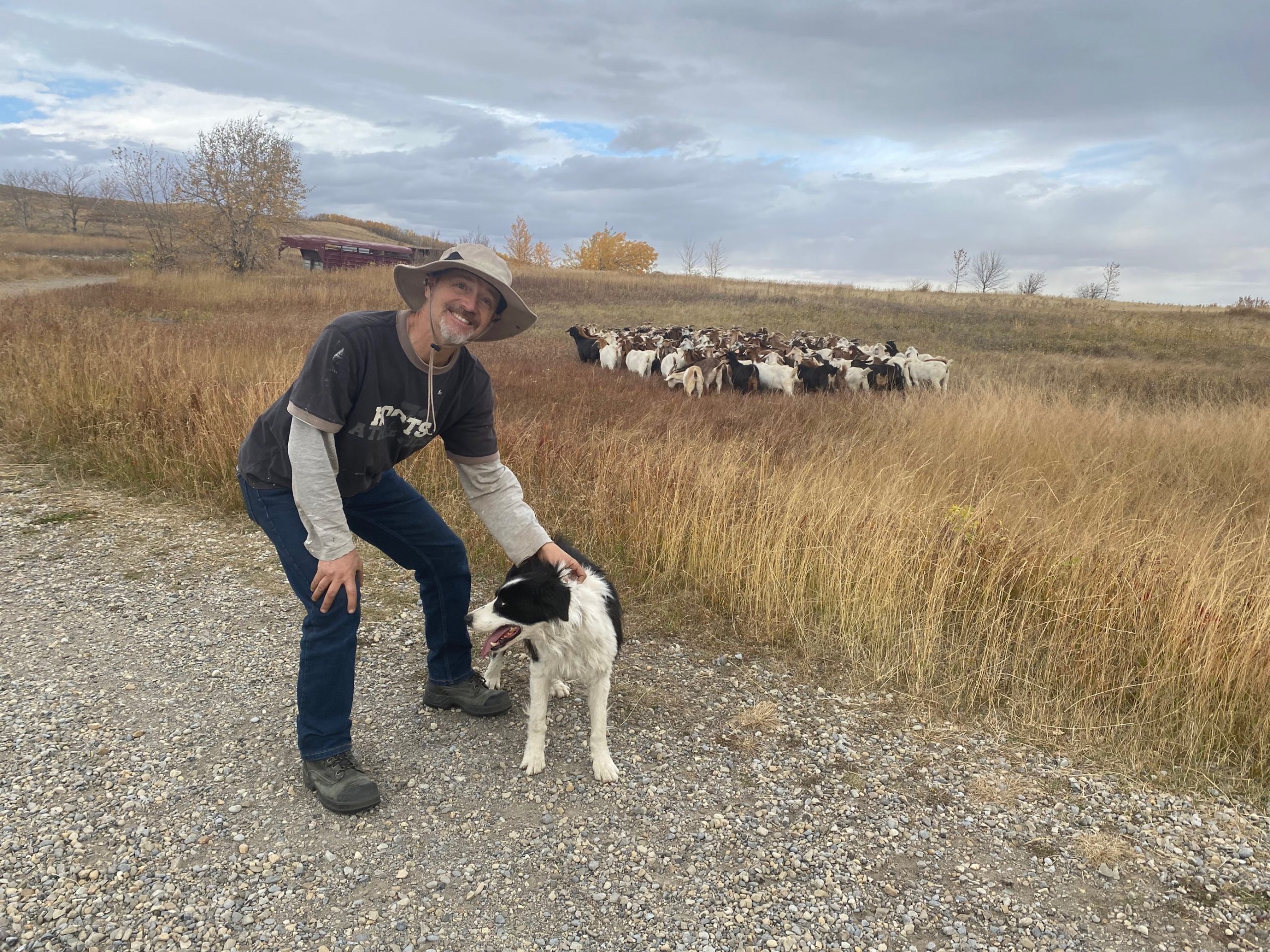 Trent, a goat herder, poses for a photo with Chance his border collie in the Rubbing Stone Hill zone within Nose Hill Park in Calgary