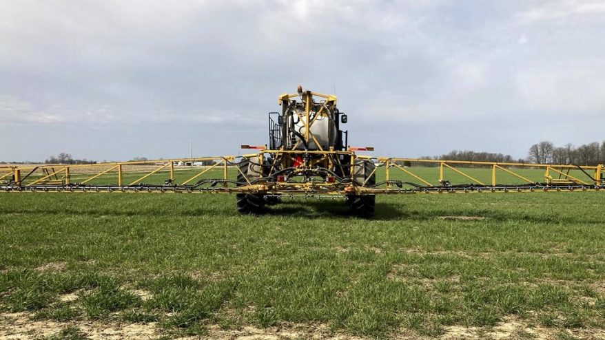 A picture of a farming driving a spray tractor