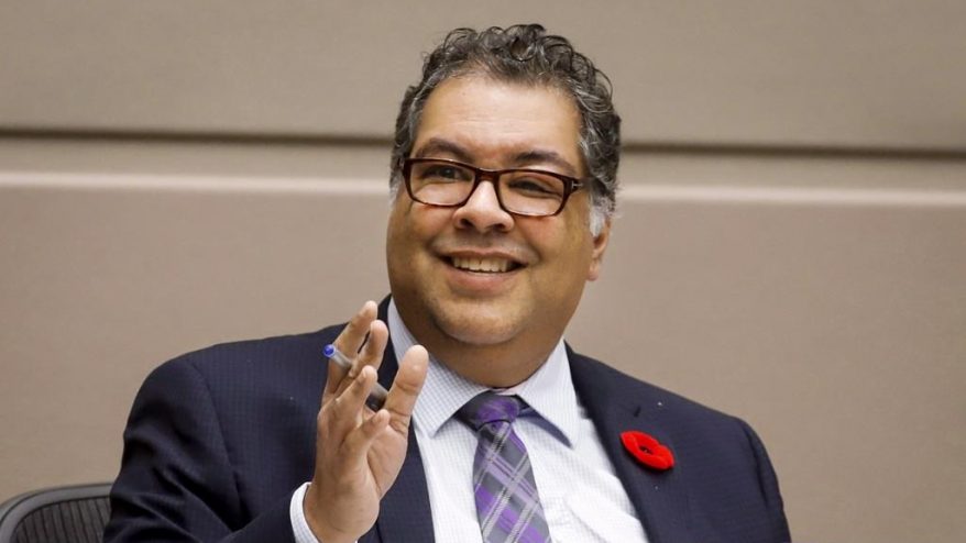 Naheed Nenshi raises his hand while speaking at a city council meeting