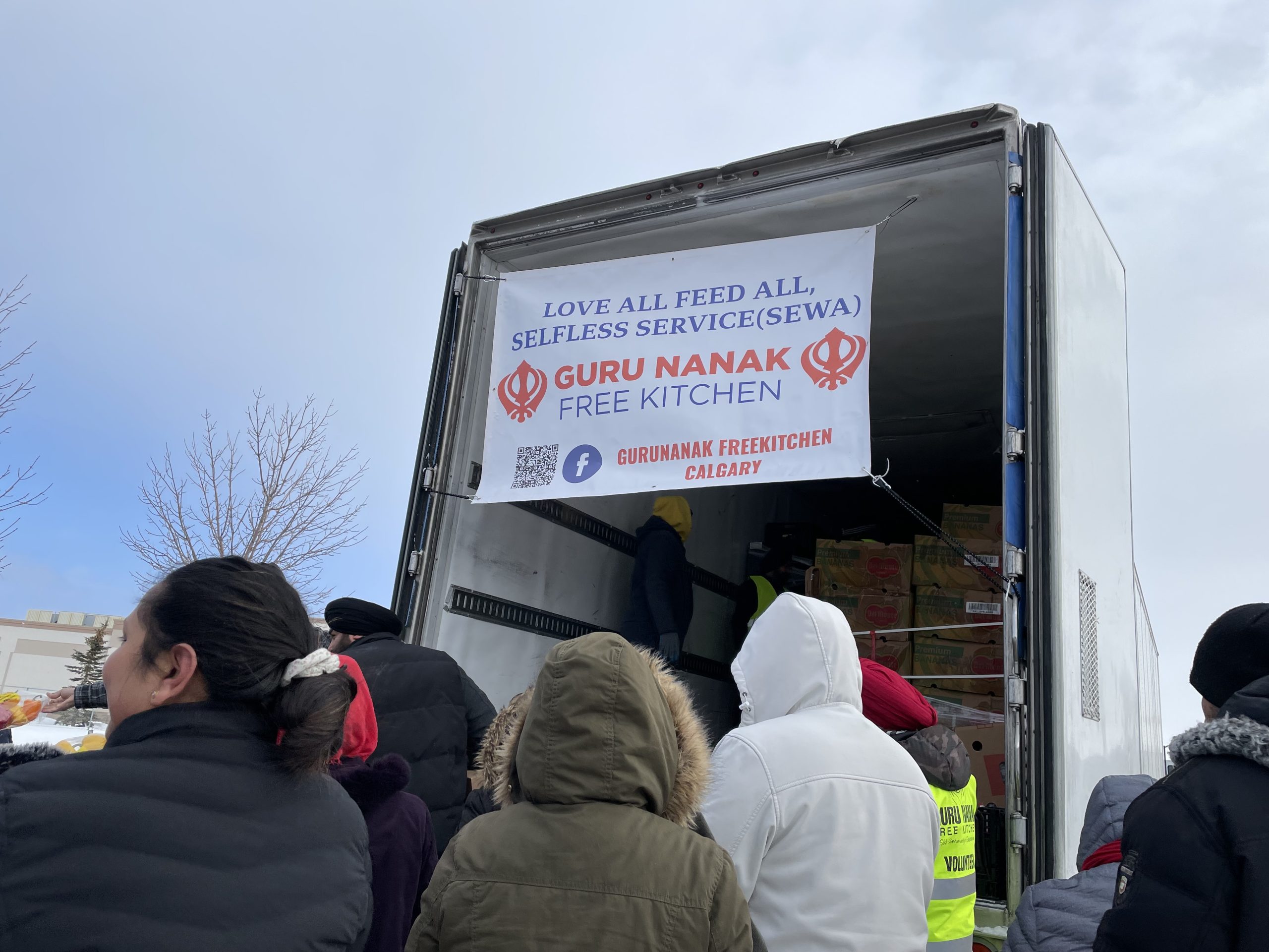 people wearing coats standing outside big white truck