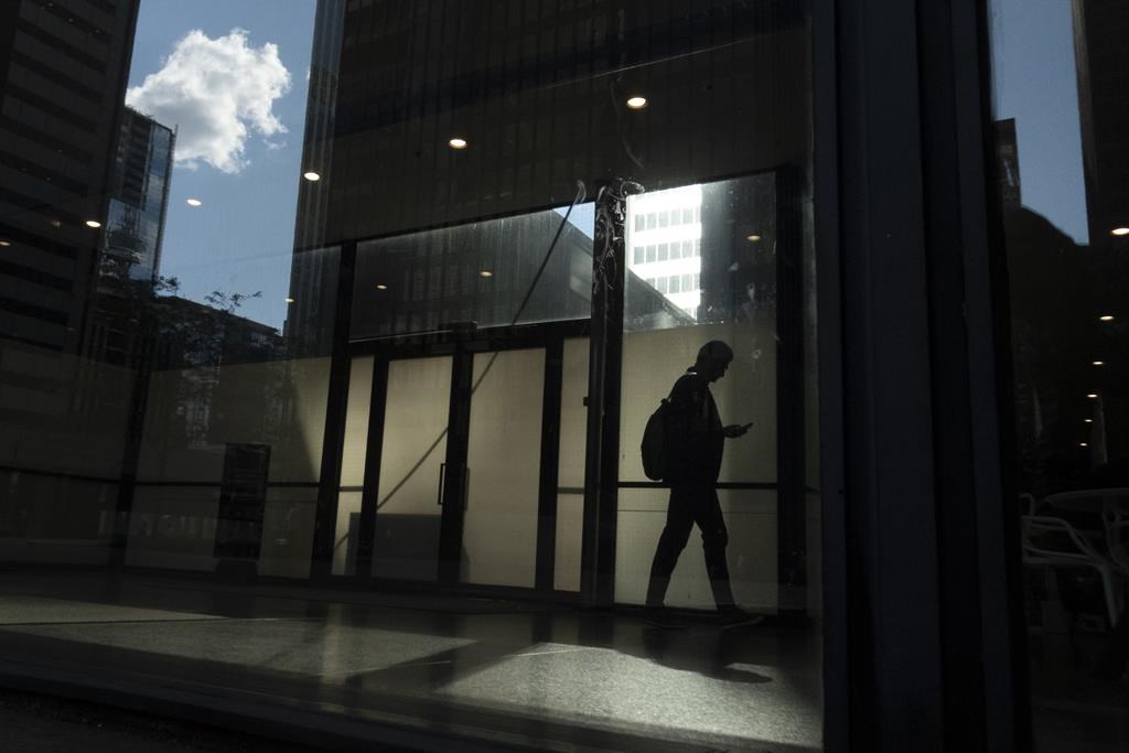 A man walks though a downtown Toronto office building with other buildings reflected in a window