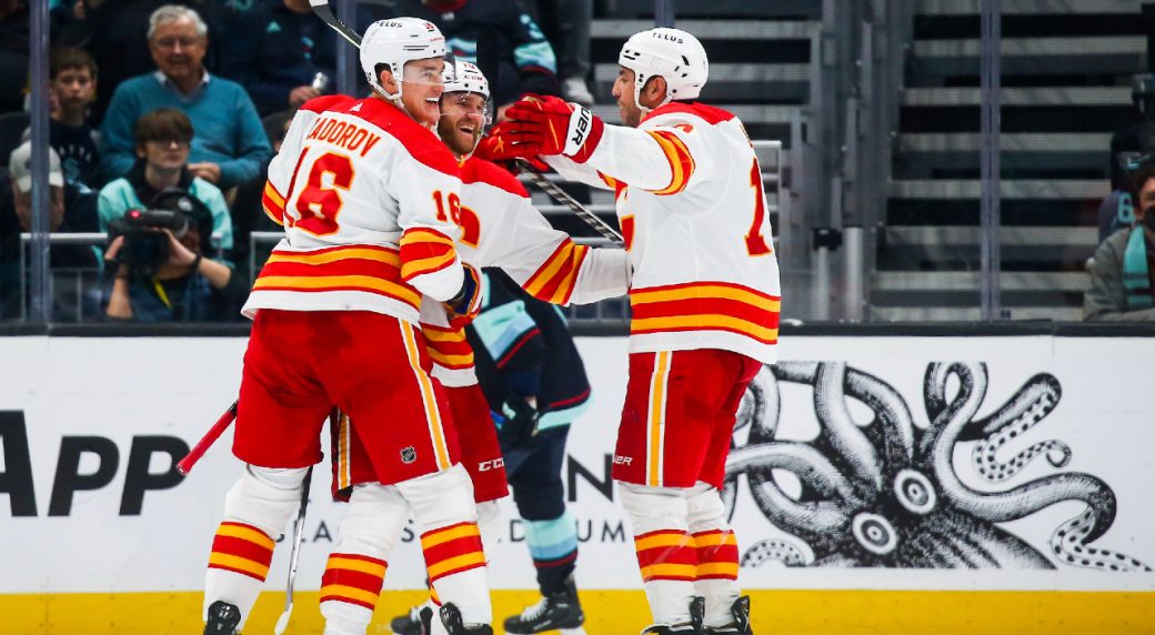 Calgary Flames center Jonathan Huberdeau, center, celebrates his goal against the Seattle Kraken with Nikita Zadorov (16) and Milan Lucic, right, during the third period of an NHL hockey game