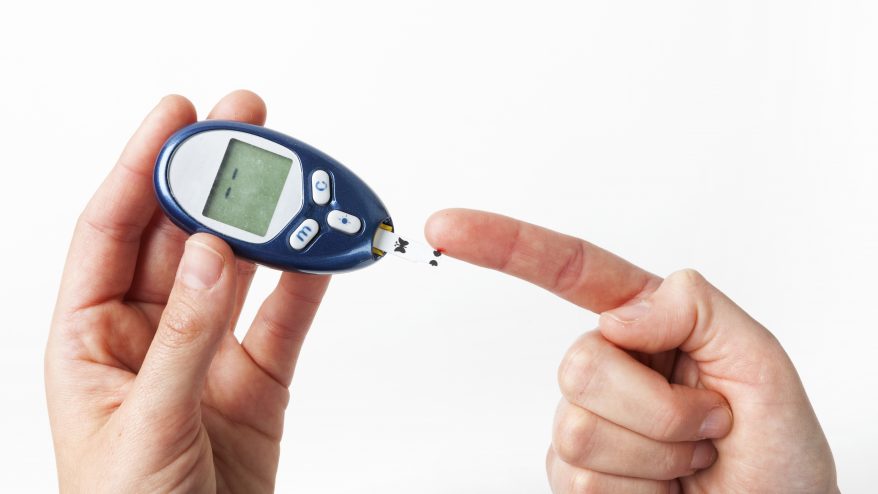 A photo showing a person using a small machine to read blood sugar level