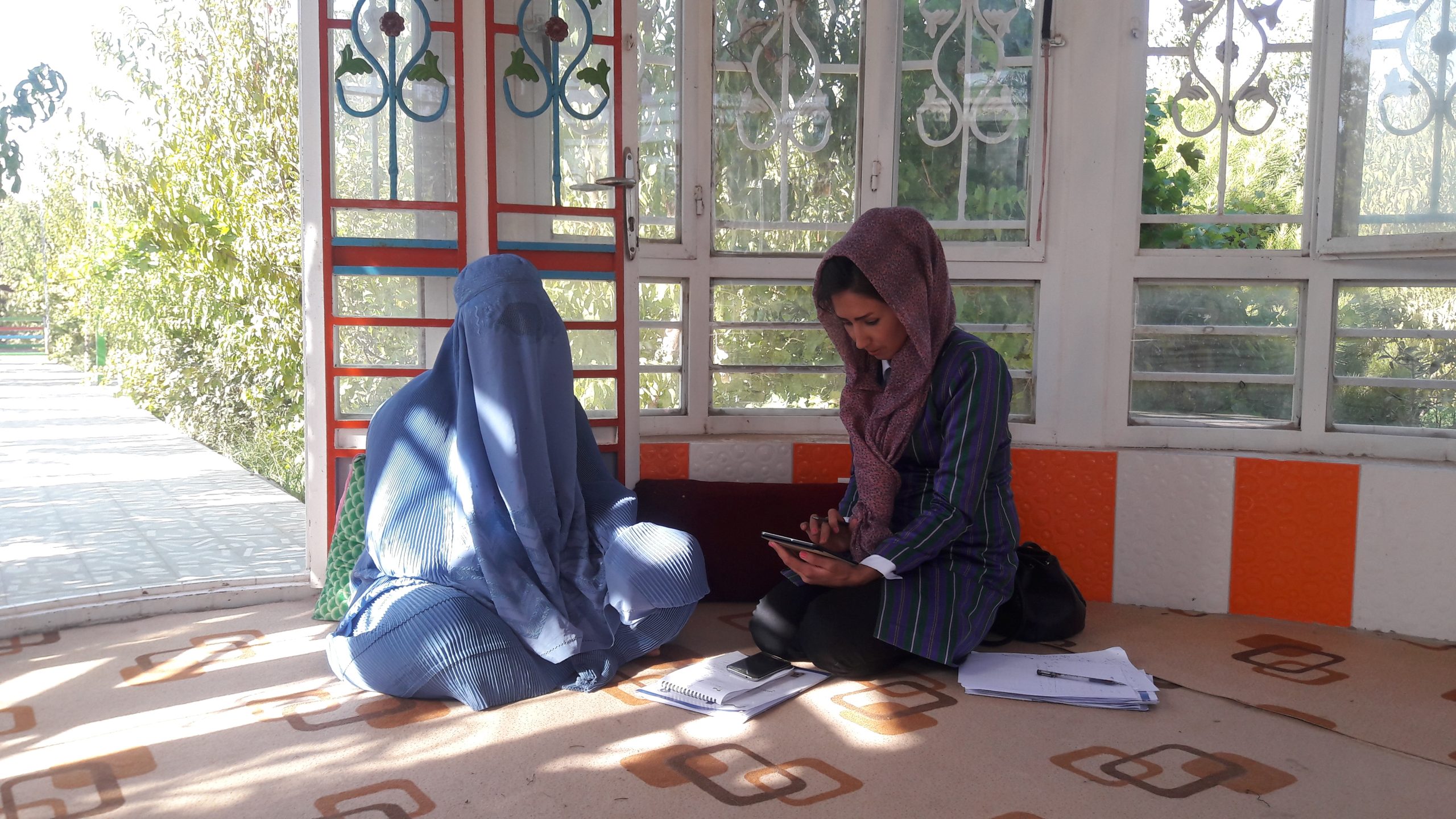 Fatima Roshanian, right, speaks with a woman and takes notes in Afghanistan