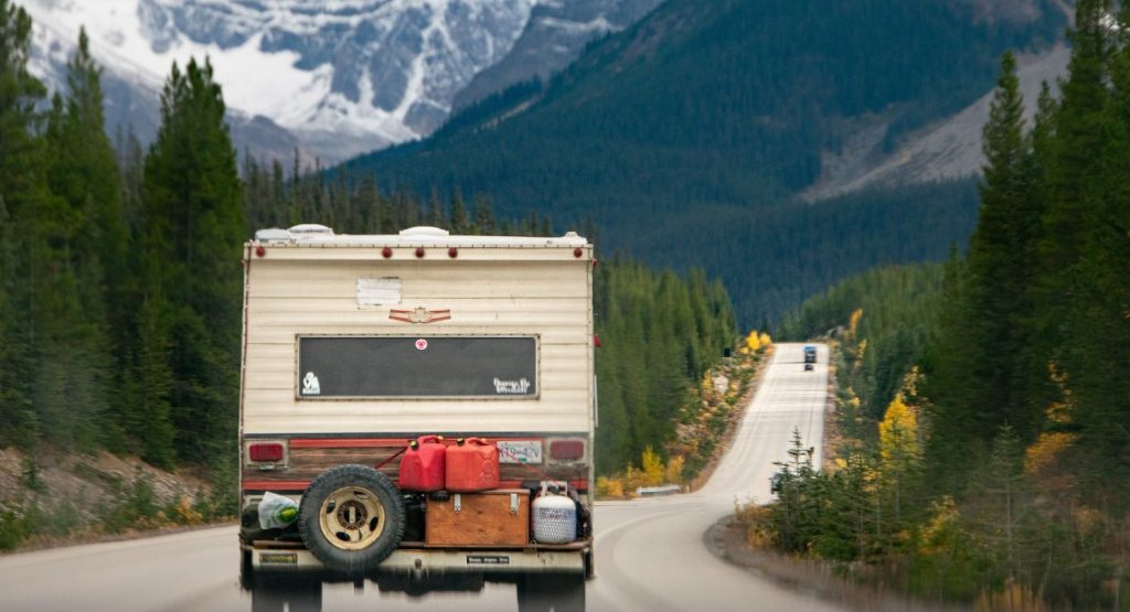 An RV drives down a road towards Banff, Alta
