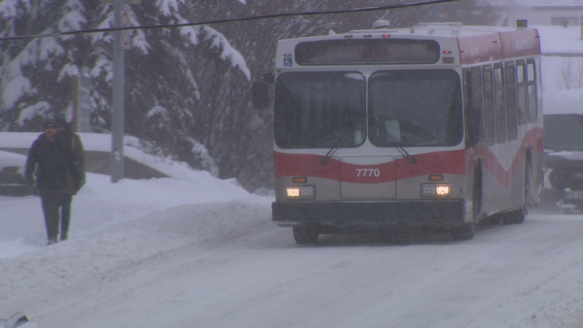 A Calgary Transit bus drives on the snow-covered road in Calgary