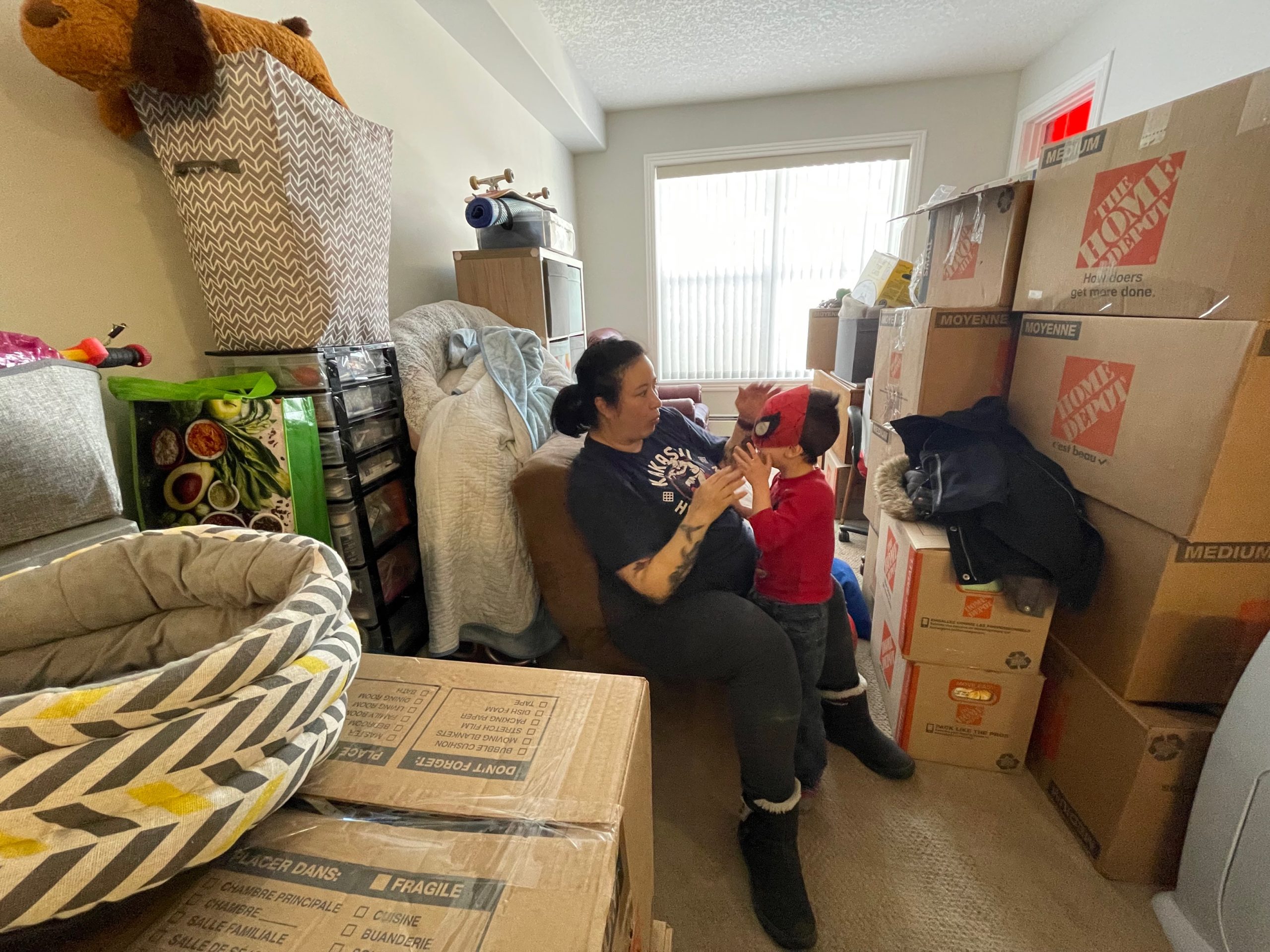 Zena Ukisu, left, inspects her son Elliot's mask inside their home in Calgary