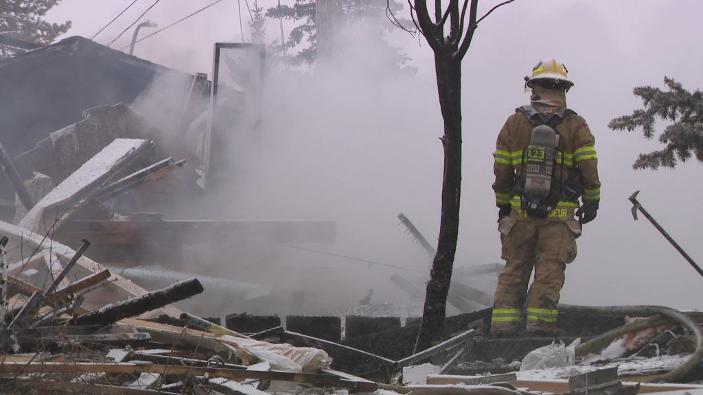 A lone firefighter looks at a home that was destroyed in an explosion in northeast Calgary