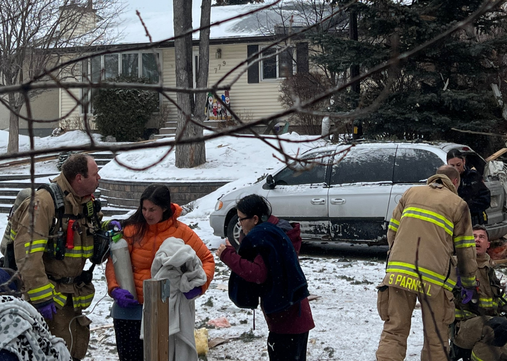 Calgary firefighters attend to people in the area of a home caught in the centre of an explosion in Marlborough in northeast Calgary