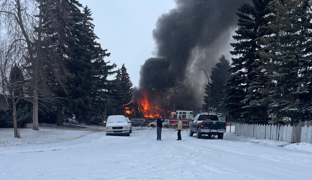 Two people talk in the foreground of a fire that was caught in an explosion in Marlborough in northeast Calgary