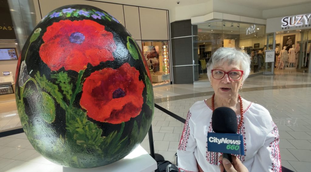 Artist Tatianna O'Donnell stands next to her painted Pysanky Easter egg at the Southcentre Mall in Calgary