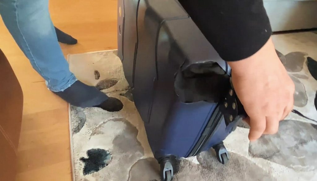 A man holds luggage that arrived with damage at the bottom in Calgary 