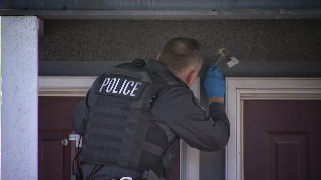 A Calgary police officer pulls a bullet from an apartment building in Calgary