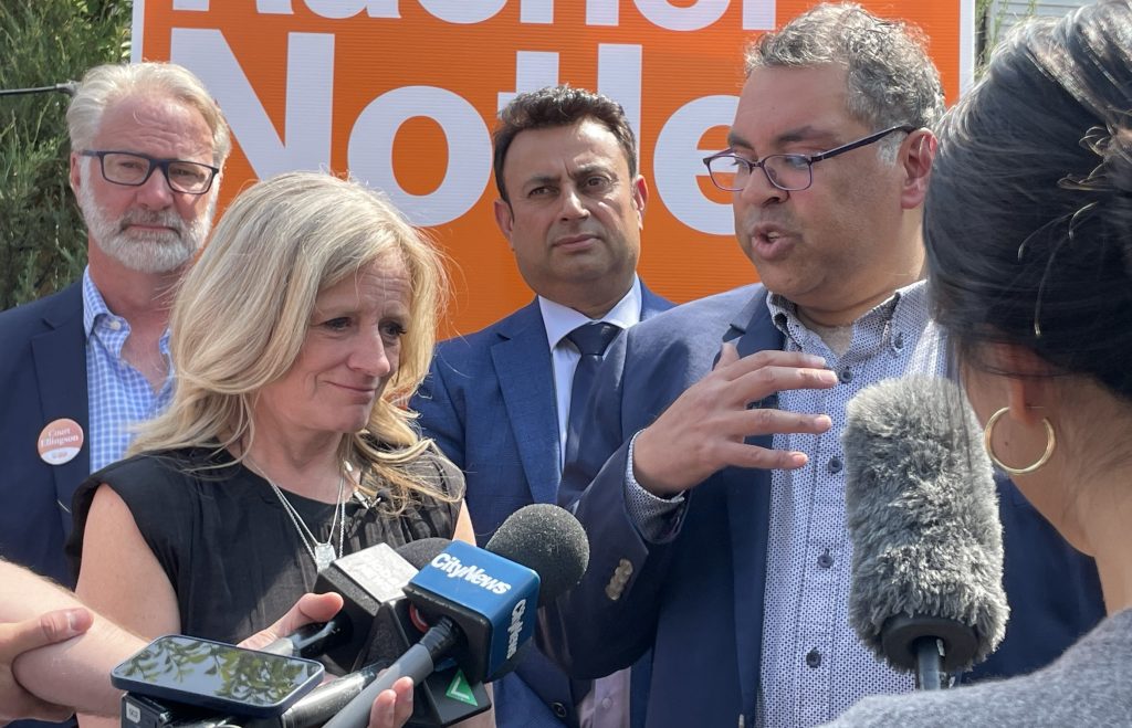 NDP leader Rachel Notley, left, and former Calgary mayor Naheed Nenshi speak with reporters in the foreground in Calgary