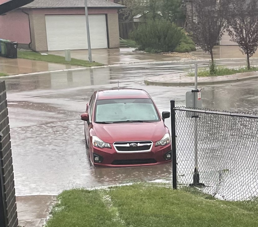 A car on a flooded road in the Panorama Hills neighbourhood in Calgary