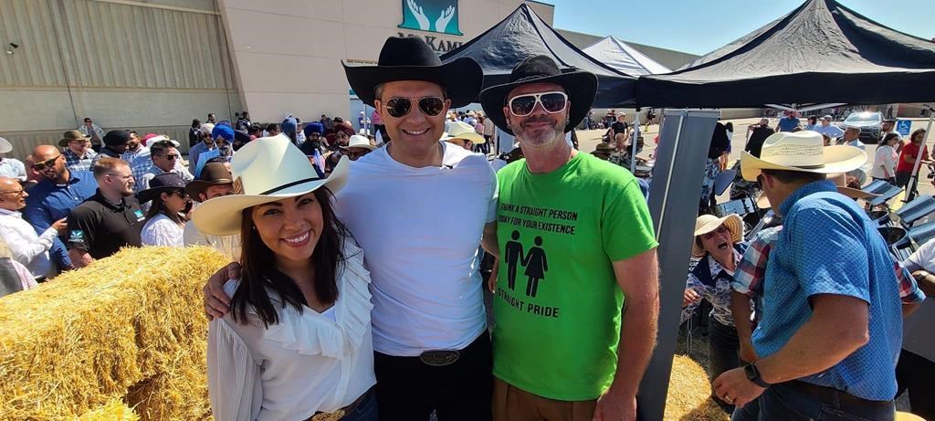Federal Conservative Leader Pierre Poilievre and his wife, Anaida, pose for a photo with an unidentified man wearing a "straight pride" T-shirt during a Calgary Stampede event in Calgary
