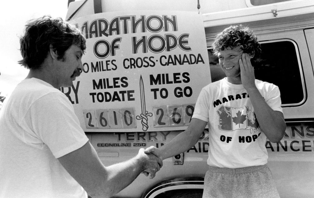 Terry Fox shaking a man's hand in front of the "Van of Hope"