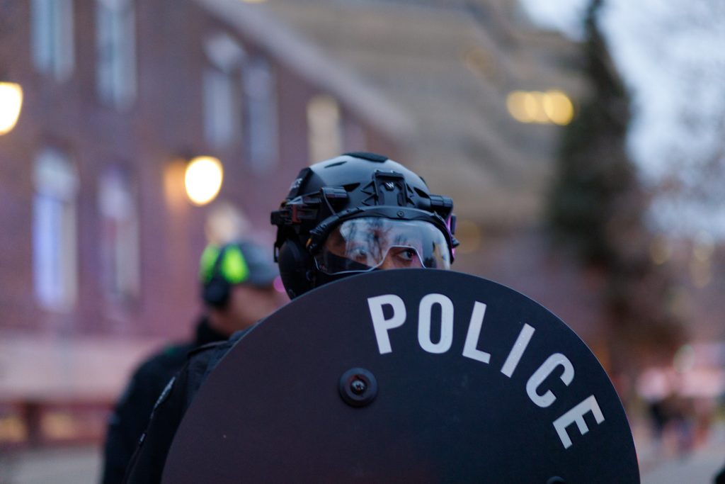 A Calgary police officer in riot gear holds a shield as he meets with pro-Palestine protestors on Macleod Trail and 5 Avenue SE in downtown Calgary