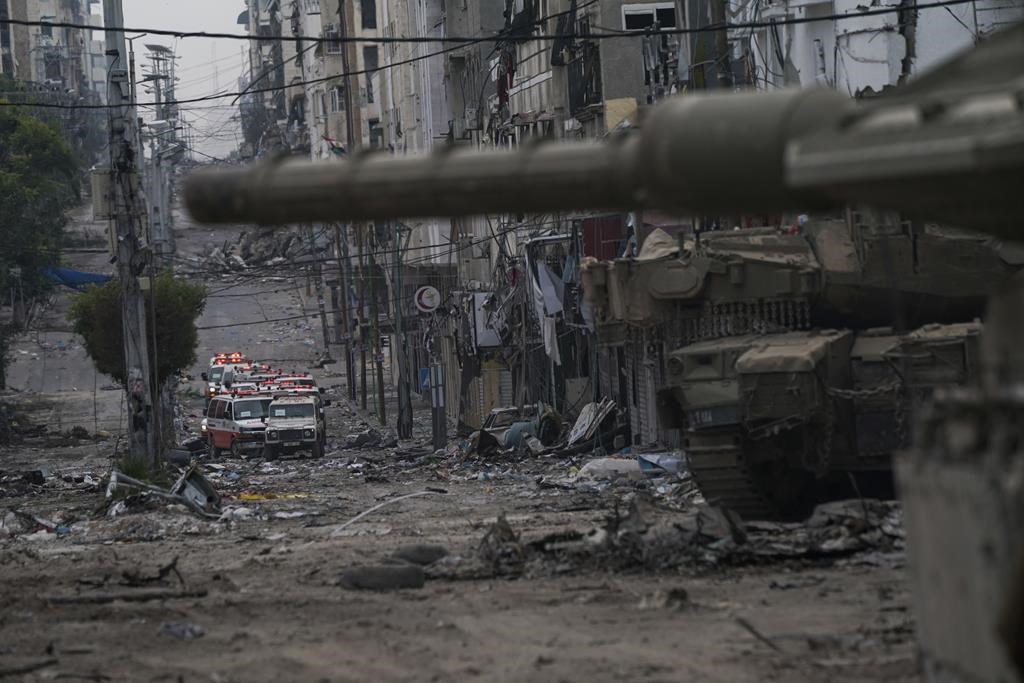 Ambulances are seen on a road near an Israeli forces tank during an Israeli army ground operation in the Gaza Strip