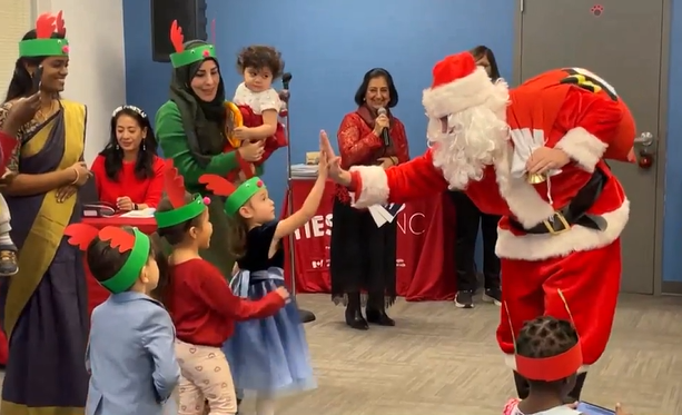 Santa Claus, right, high-fives a young girl at the Immigrant Education Society in Calgary