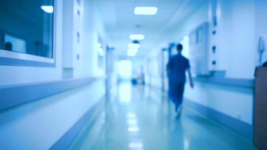 A healthcare worker walks down a hospital hallway