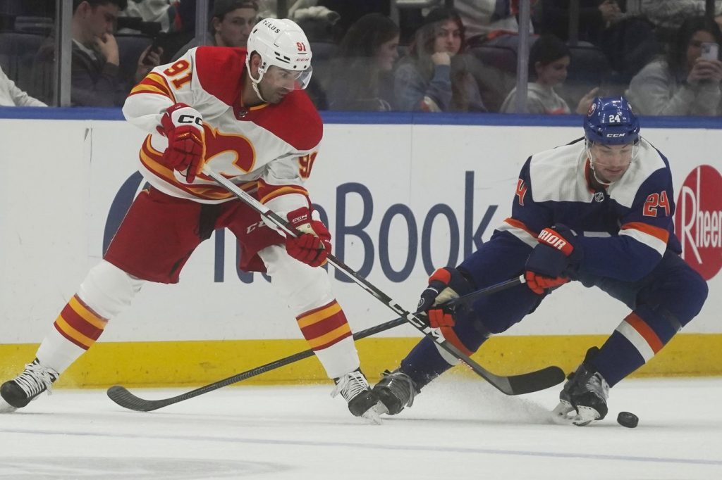 Calgary Flames' Nazem Kadri, left, and New York Islanders defenseman Scott Mayfield, right, jostle for position during the second period of an NHL hockey game, Saturday, Feb. 10, 2024, in New York