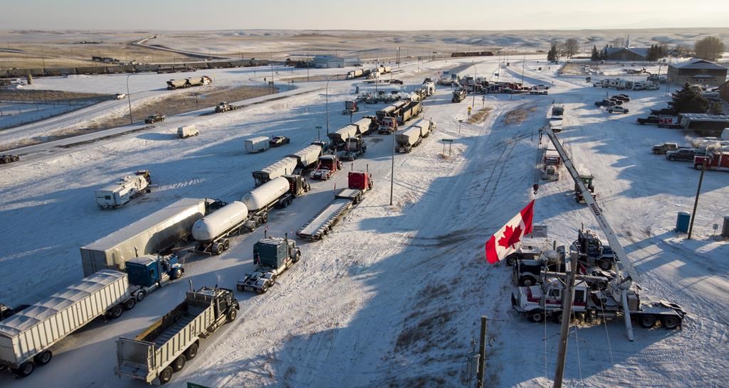 A truck convoy of anti-COVID-19 vaccine mandate demonstrators block the highway at the busy U.S. border crossing in Coutts, Alta., Wednesday, Feb. 2, 2022. Opening arguments are scheduled today in the trial for three men charged for their role in the blockade of the Canada-U.S. border at Coutts, Alta. THE CANADIAN PRESS/Jeff McIntosh