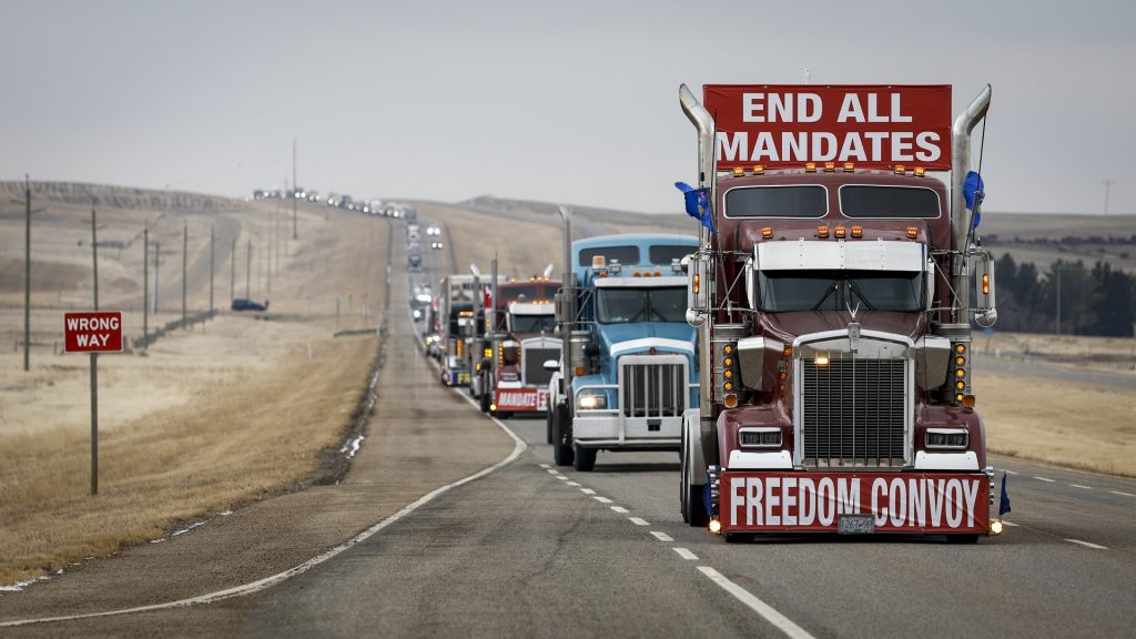 Anti-COVID-19 vaccine mandate demonstrators leave in a truck convoy after blocking the highway at the busy U.S. border crossing in Coutts, Alta., Tuesday, Feb. 15, 2022.THE CANADIAN PRESS/Jeff McIntosh
