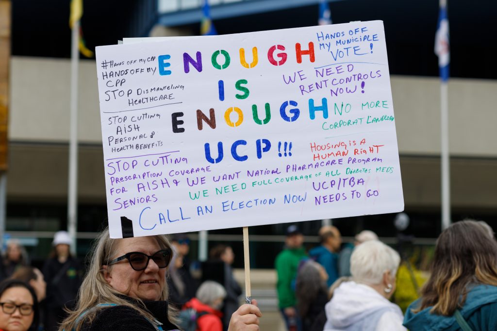 Cassandra Pollock holds a sign that reads "Enough is enough" at City Hall in Calgary on Saturday