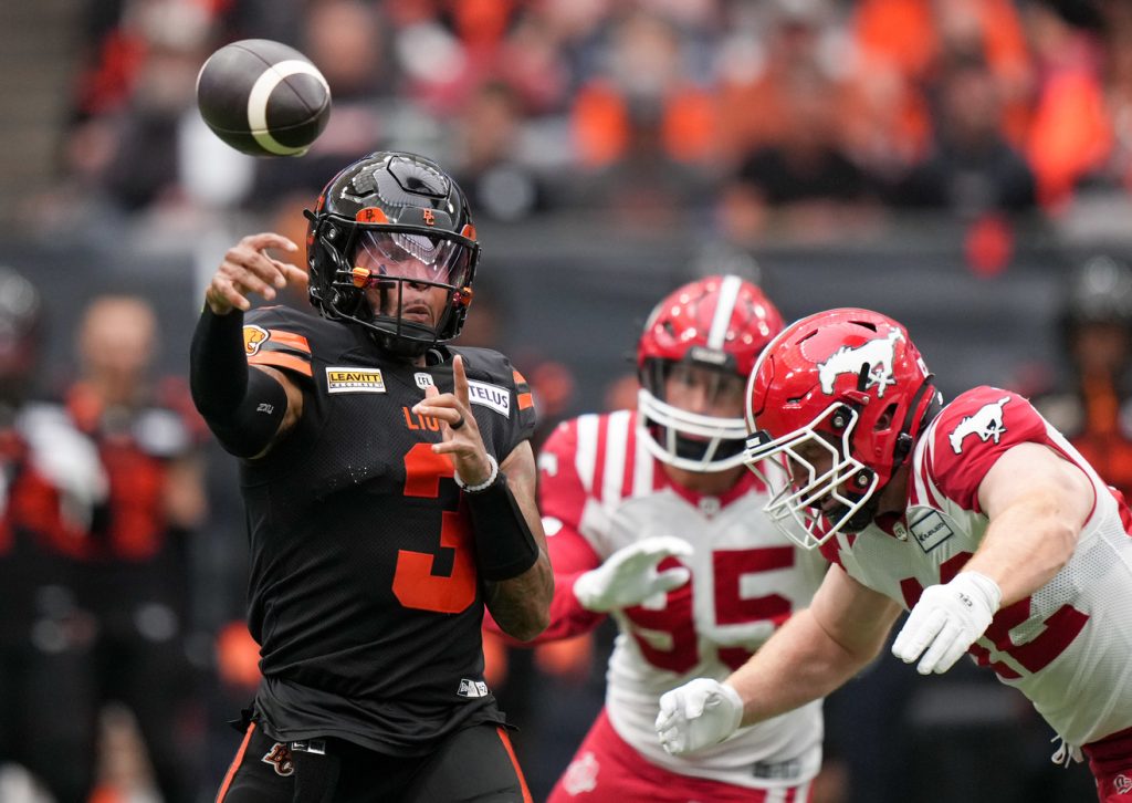 B.C. Lions quarterback Vernon Adams Jr., left, passes while being pursued by Calgary Stampeders' Micah Teitz during the first half of a CFL football game, in Vancouver, on Saturday