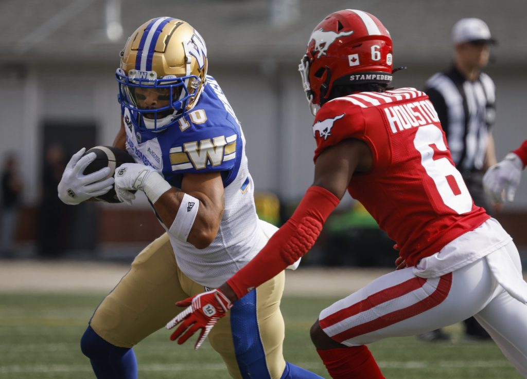 Winnipeg Blue Bombers' Nic Demski (10) runs the ball as Calgary Stampeders' Demerio Houston (6) closes in during first half CFL football action in Calgary, Alta., Saturday, June 29, 2024