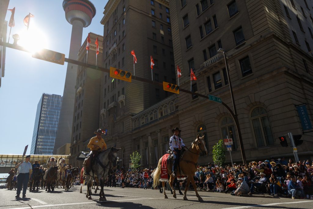 Owen Crow Shoe, right, marches down 9 Avenue past the Palliser Hotel as part of the 2024 Calgary Stampede Parade in downtown Calgary