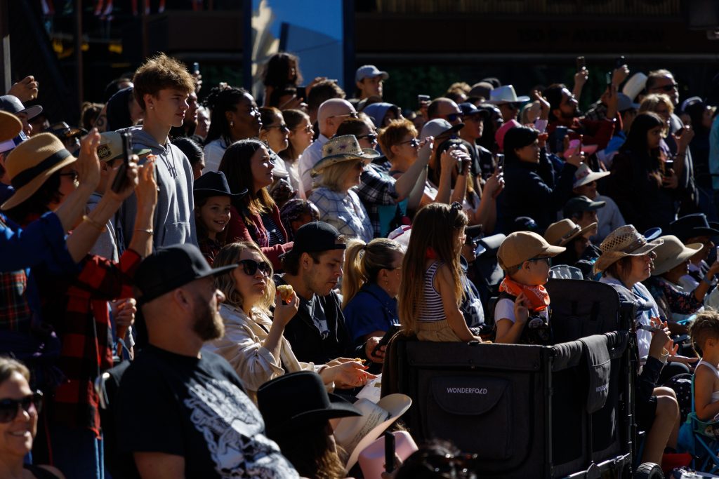 Several dozen people look on, snap photos, or capture video at the 2024 Stampede Parade in downtown Calgary on Friday, July 5, 2024. Thousands of people were in attendance and were along 9 Avenue and 7 Avenue