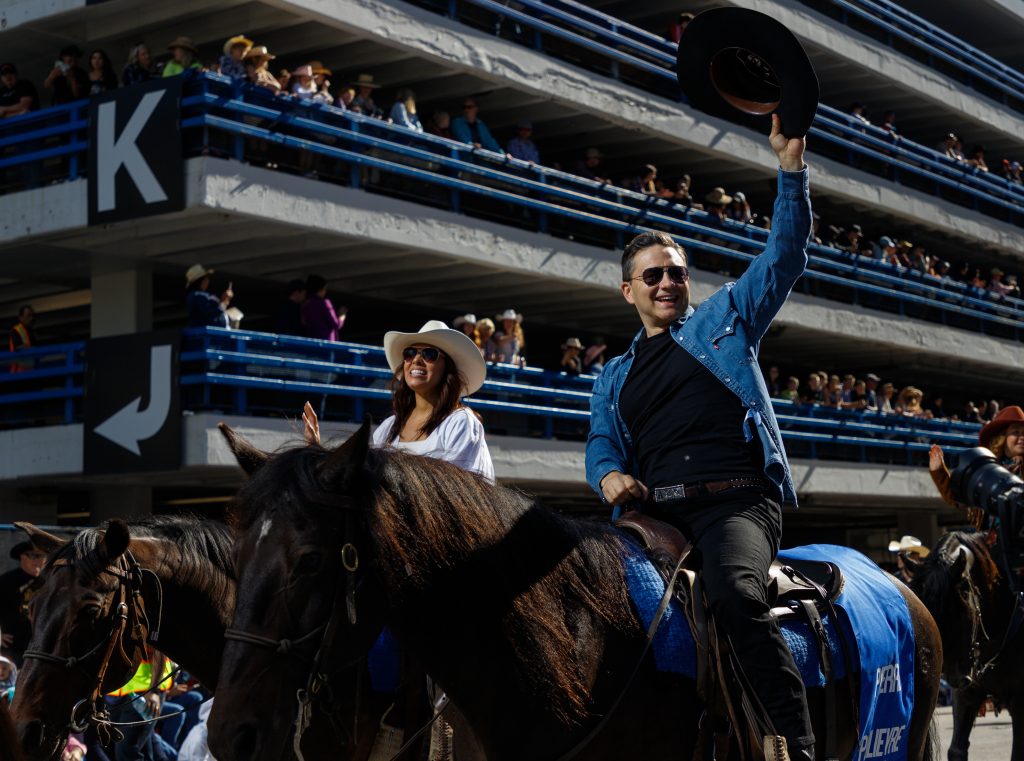 Conservative Party Leader Pierre Poilievre, right, waves his hat to the crowd while his wife Anaida waves her hand to the crowd as part of the 2024 Stampede Parade festivities in downtown Calgary