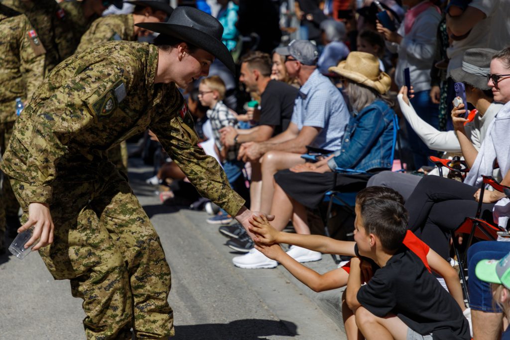 A Canadian soldier receives high-fives from children at the side of the Stampede Parade in downtown Calgary 
