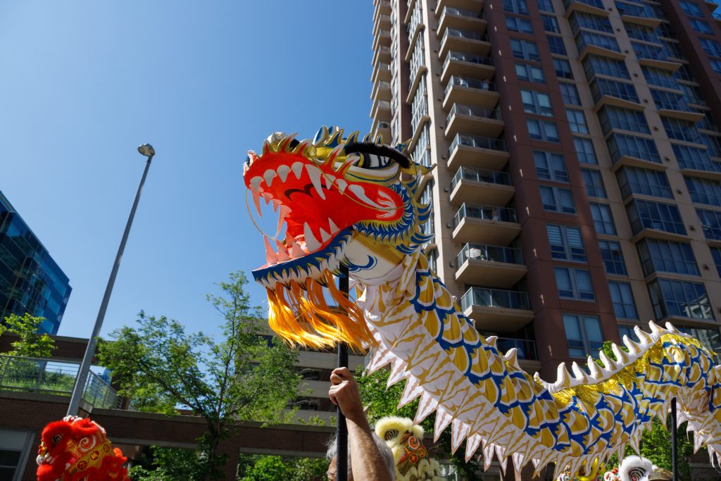 A dragon sails above participants in the Stampede Parade kicks in downtown Calgary on Friday, July 5, 2024