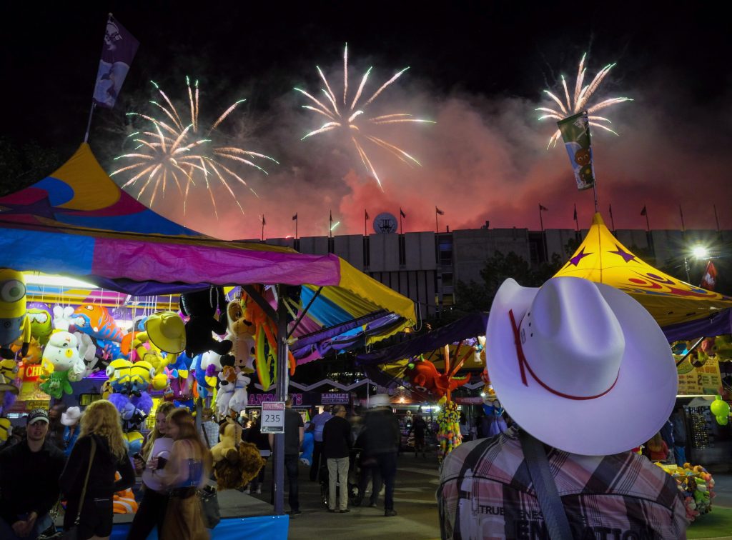 A visitor watches the fireworks display from the midway at the Calgary Stampede in Calgary, Saturday, July 9, 2016. THE CANADIAN PRESS/Jeff McIntosh