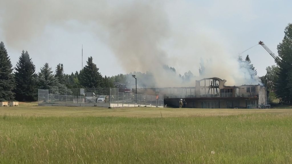 Rocky View County firefighters watch as crews douse a fire in a home in Lower Springbank west of Calgary on