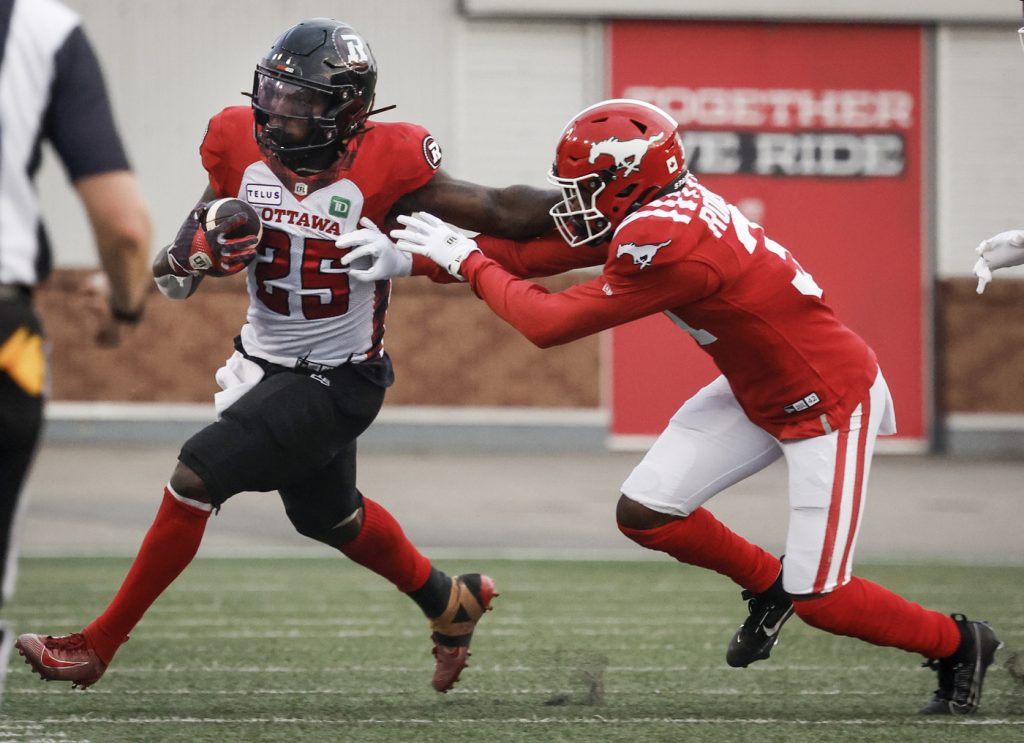 Ottawa Redblacks' Ryquell Armstead (25) is tackled by Calgary Stampeders' Tre Roberson (31) during first half CFL football action in Calgary